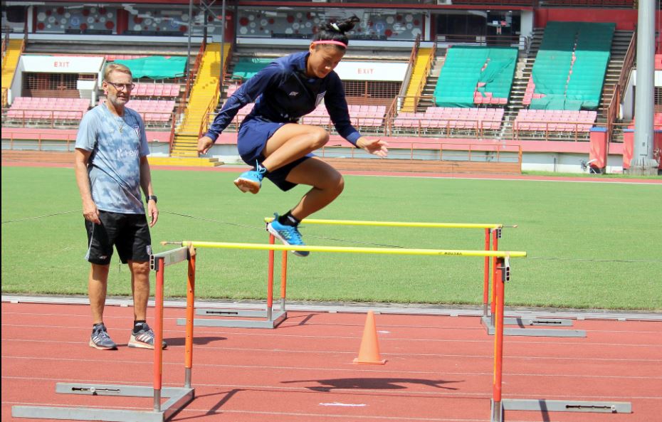 Sweety Devi R jumps the hurdles as Thomas Dennerby L looks on