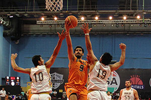Ranbir Singh of Mumbai Challengers in orange rises for the layup against two Haryana defenders