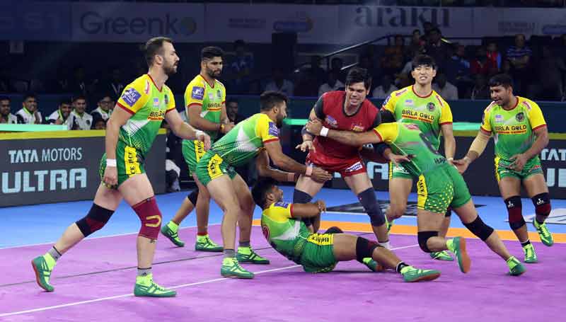 Defending champion teams captain Rohit Kumar makes his raid through the tough grip of Patna Pirates